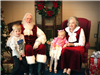 Mr. and Mrs. Santa with two small children in their lap. 