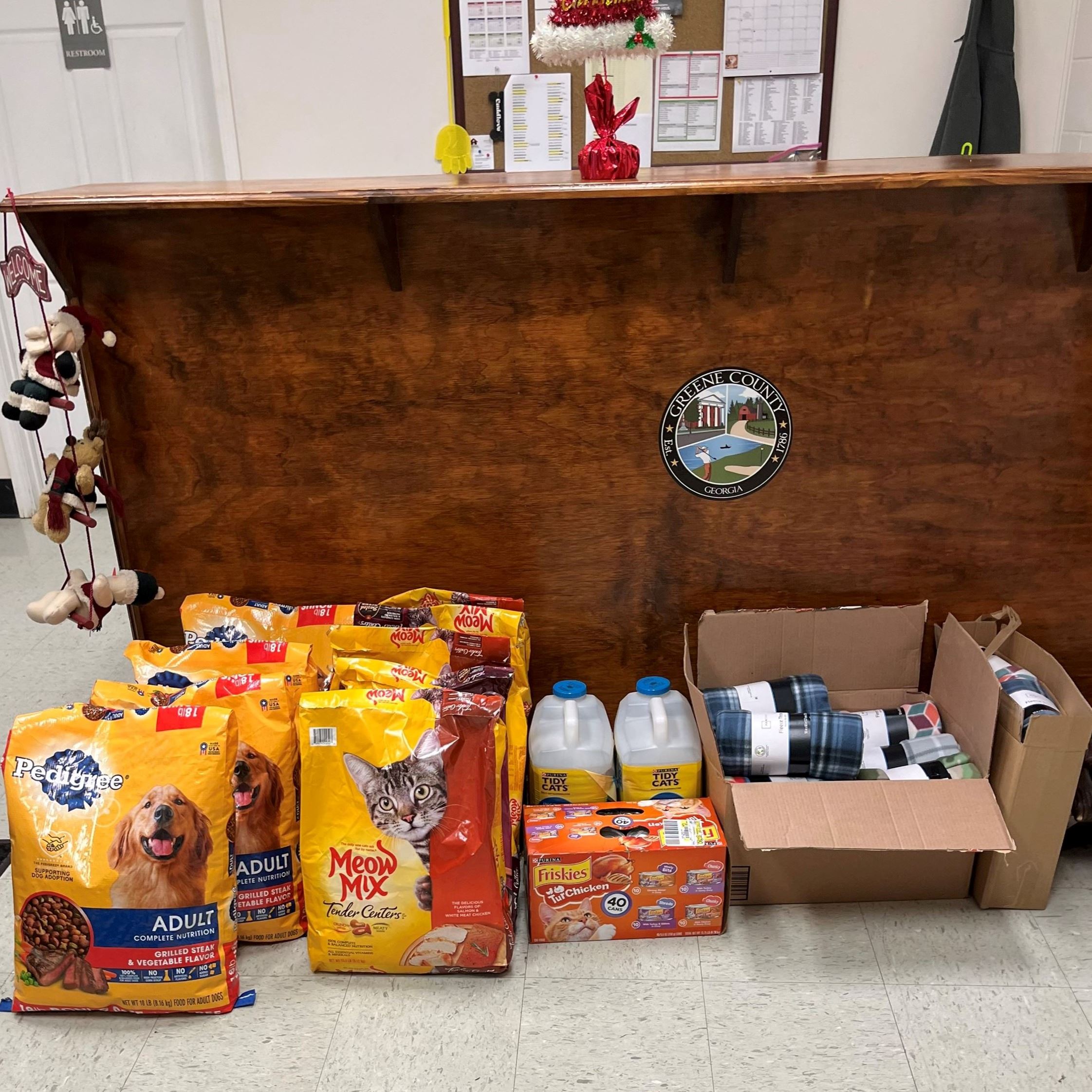 Bags of cat and dog food sitting on the ground in front of a desk. 