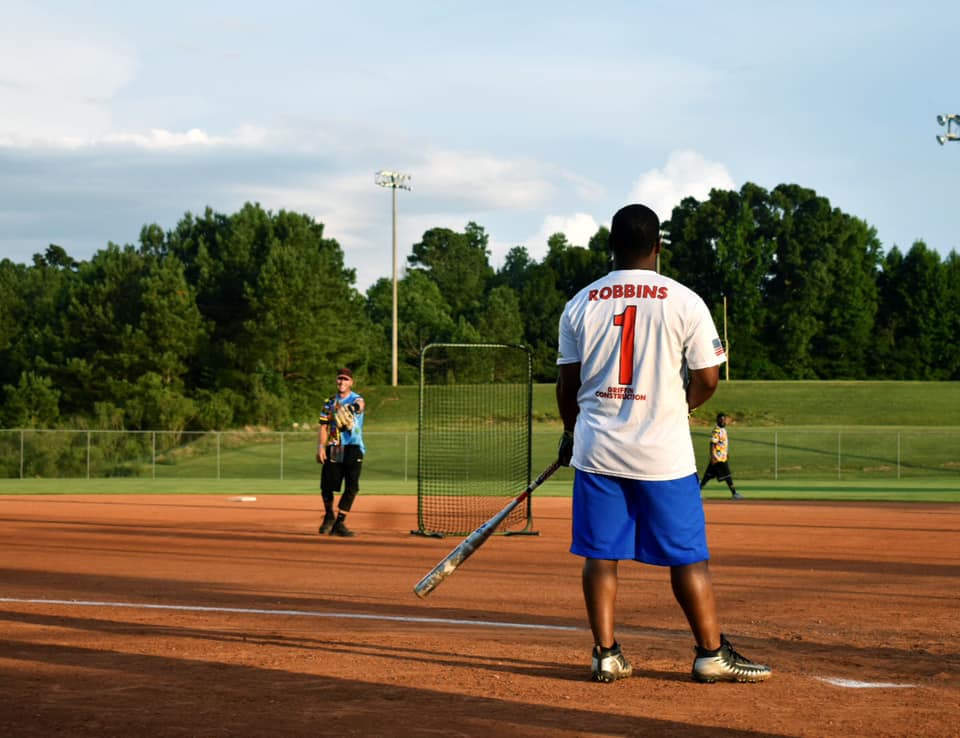 Men playing softball.  Pitcher pitching to a batter.  